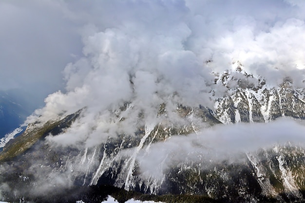 Montanhas nevadas com pico nas nuvens, céu azul Cáucaso