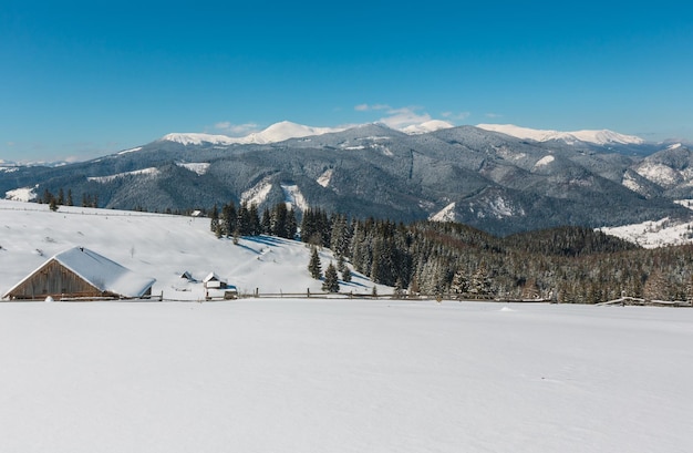 Montanhas nevadas de inverno e fazenda solitária