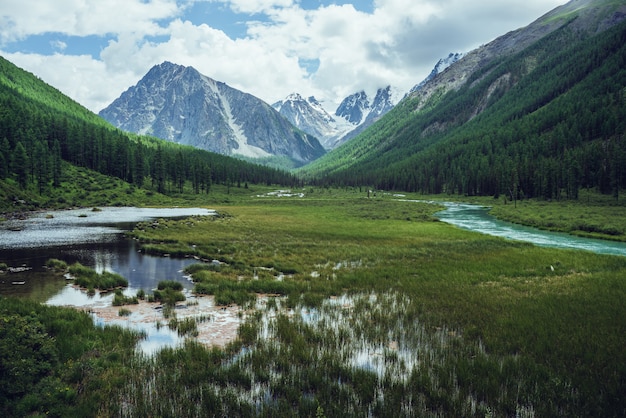 Montanhas nevadas, lago alpino e rio da montanha.