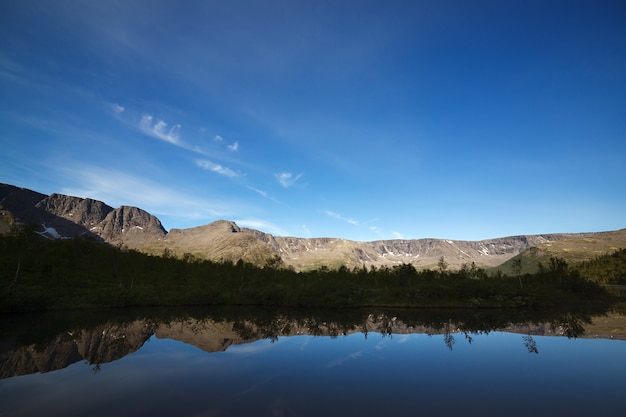 Montanhas refletidas na superfície lisa do lago ao amanhecer