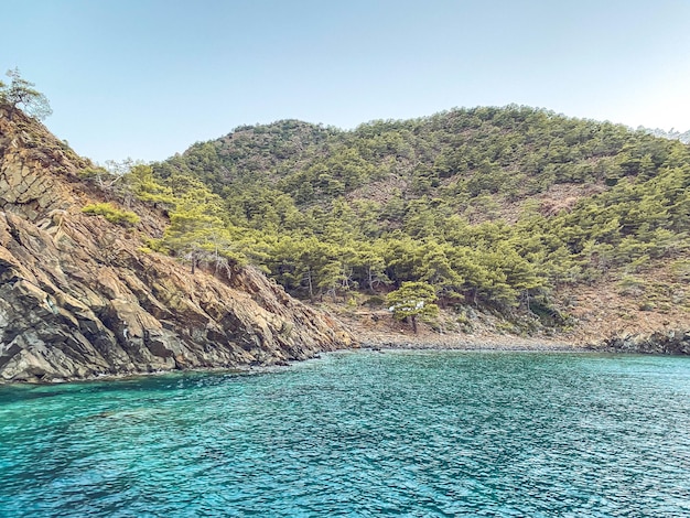 Montanhas verdes com plantas acima no mar uma pequena ilha com uma rocha no centro turístico