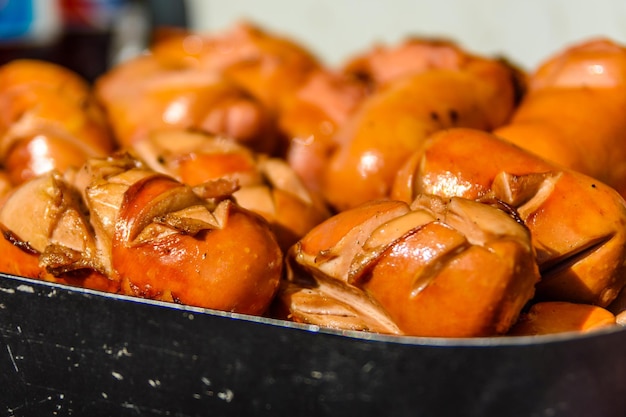 Montão das salsichas fritas na bandeja de aço