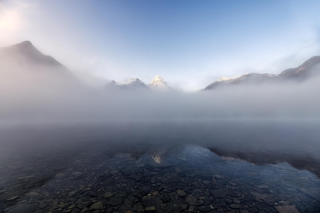 Monte Assiniboine em reflexão azul enevoada no Lago Magog no Parque Provincial, BC, Canadá