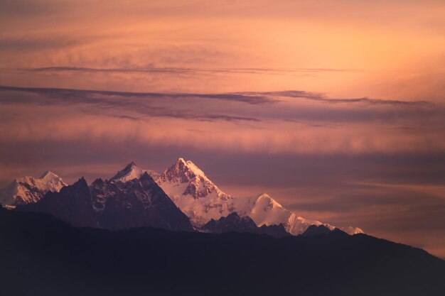 Monte kangchenjunga, pico das montanhas do himalaia durante o nascer do sol, picos brancos dourados cobertos de neve sob cobertura de nuvens, como visto de kalimpong, na índia