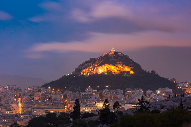 Monte Lycabettus elevándose por encima de los tejados del casco antiguo al atardecer en Atenas, Grecia