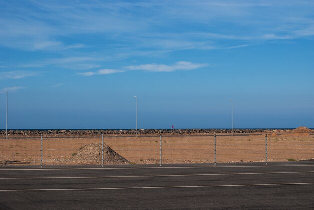 Un montículo de arena roja sobre un fondo de cielo azul cerca de la carretera