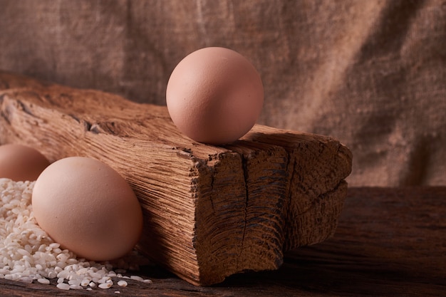 Montón de arroz y huevos sin cocer en la mesa de madera.