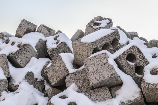 Montón de bloques de hormigón de ladrillos de construcción en el sitio de construcción bajo la nieve