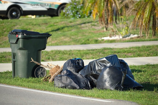 Montón de bolsas de basura negras y cubos de basura de plástico al aire libre en la calle rural Problemas de gestión de residuos