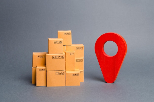 Un montón de cajas de cartón y un alfiler de posición roja para localizar paquetes y mercancías