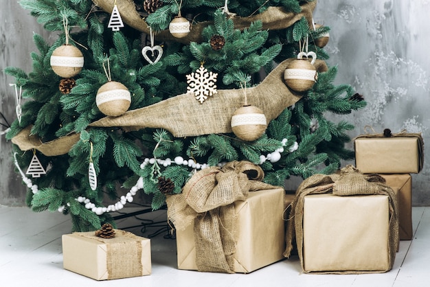 Un montón de cajas de regalo bajo el árbol de Navidad moderno decorado