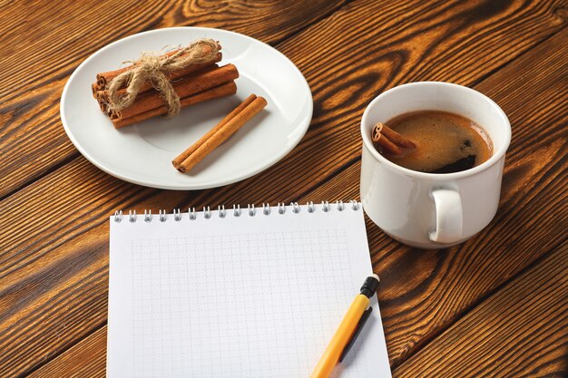 Un montón de canela tejida con una soga, una taza de café y una libreta