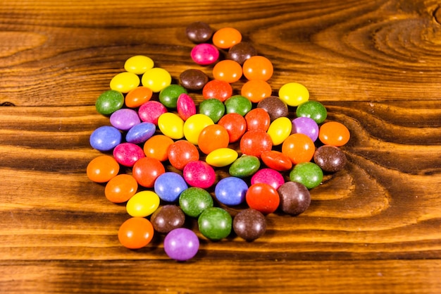 Montón de caramelos multicolores sobre una mesa de madera