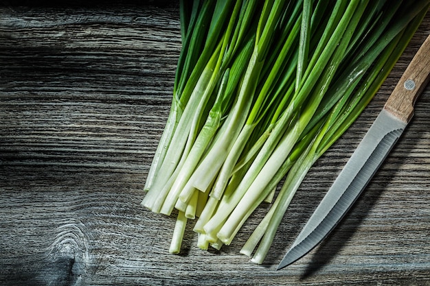 Foto montón de cebolletas verdes y cuchillo de cocina en madera vintage