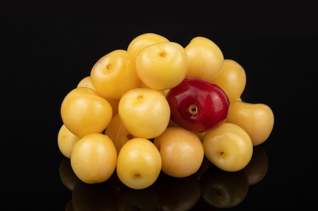 Un montón de cerezas amarillas con una baya roja en el centro.