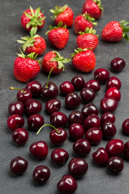 Montón de cerezas maduras y fresas en la mesa