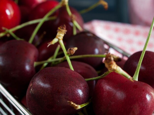 Montón de cerezas recién cosechadas en canasta de metal.