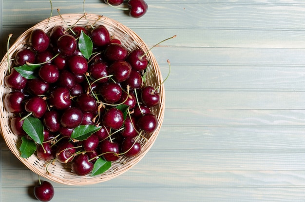 Un montón de cerezas rojas maduras en una cesta de mimbre.