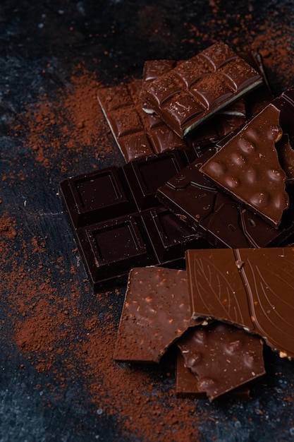 Un montón de chocolates oscuros sobre una superficie oscura con polvo rojo alrededor