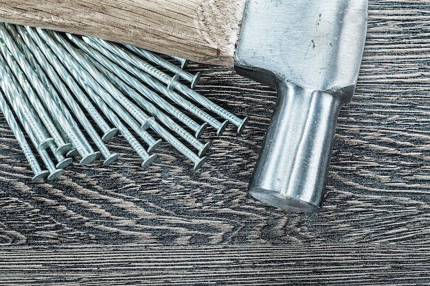 Foto montón de clavos de construcción martillo sacaclavos sobre tabla de madera