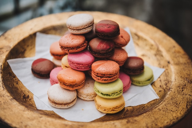 Un montón de coloridos macarons franceses o macarons en una placa dorada