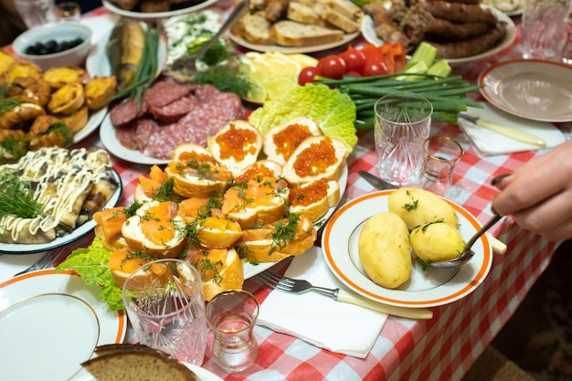 Un montón de comida diferente en la mesa del banquete y se sirven patatas hervidas con eneldo. Una gran cantidad de platos preparados en la mesa. Vacaciones en la mesa