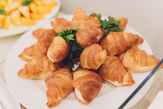 Un montón de cruasanes recién hechos en un plato blanco en el buffet en el restaurante.