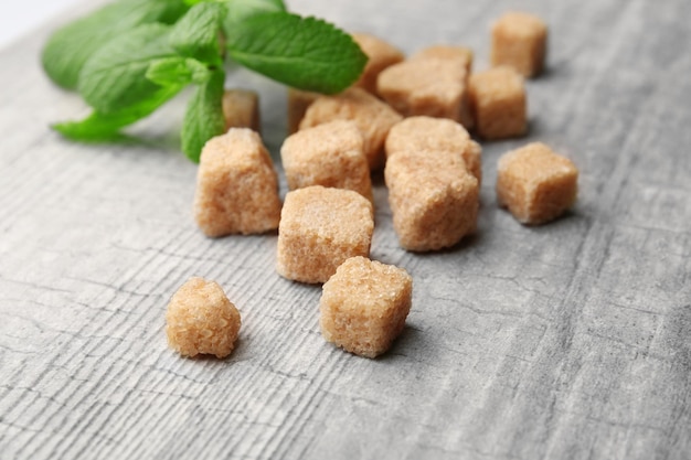 Montón de cubos de azúcar moreno y stevia sobre fondo de madera gris