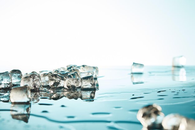 Foto montón de cubos de hielo derretidos transparentes con charcos de agua en fondo esmeralda y blanco