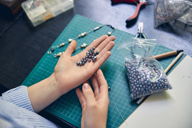 Un montón de cuentas relucientes en la mano de un experimentado bijouterie maker