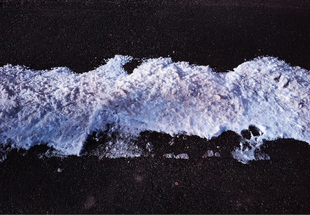 Montón curvo de nieve en el fondo de la carretera de asfalto