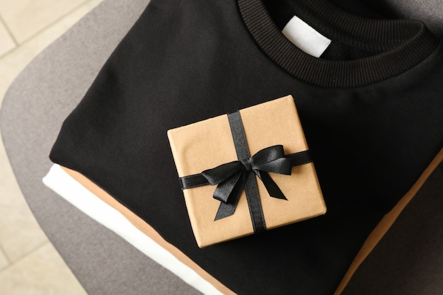 Montón de elegantes sudaderas con caja de regalo en silla