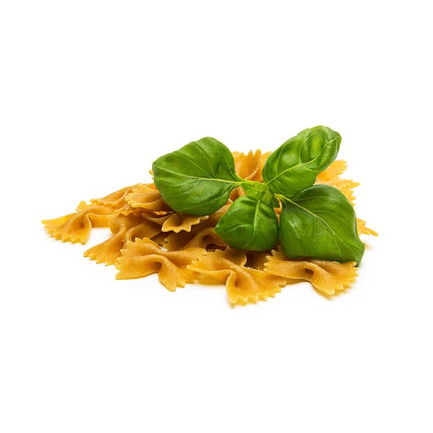 Un montón de fideos de pasta farfalle integrales con hojas de albahaca aisladas sobre fondo blanco. Tomada en estudio con una 5D mark III.