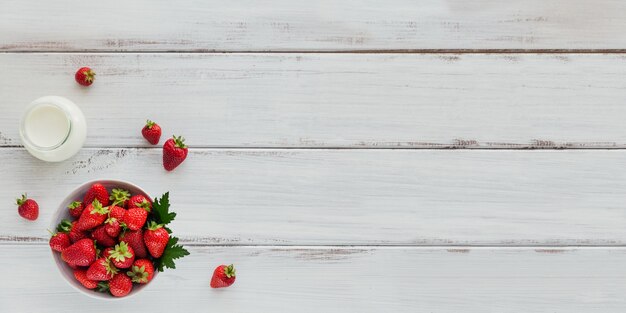 Montón de fresas frescas en cuenco de cerámica sobre superficie blanca.