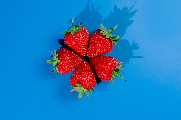 Montón de fresas en la pared azul