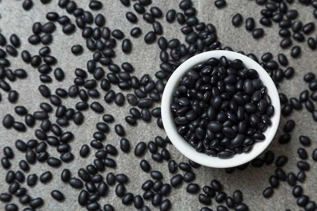 Foto un montón de frijol negro y frijol negro en un tazón blanco