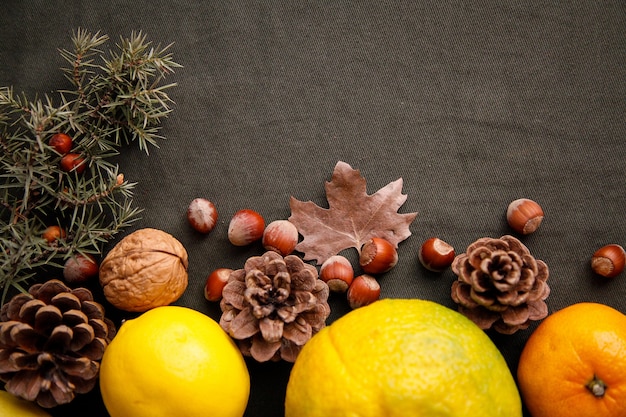 Montón de frutas frescas, conos y nueces sobre la tela verde oscuro