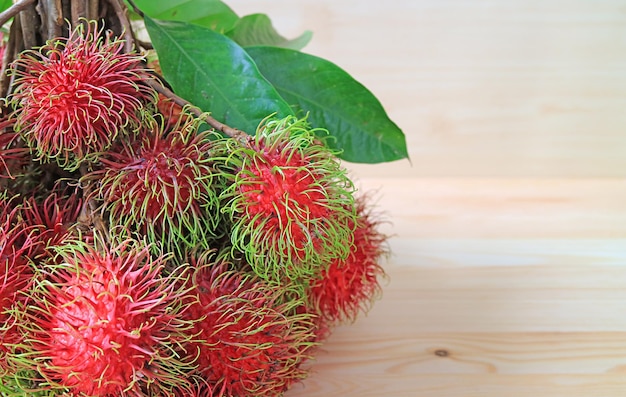 Montón de frutas frescas de rambután maduras sobre fondo de madera