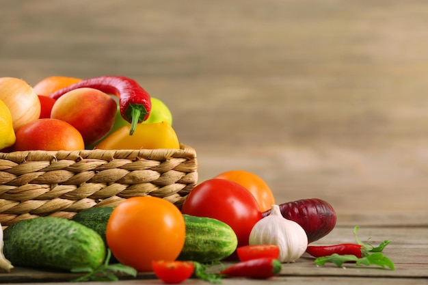Montón de frutas y verduras frescas en la cesta en la mesa de madera de cerca