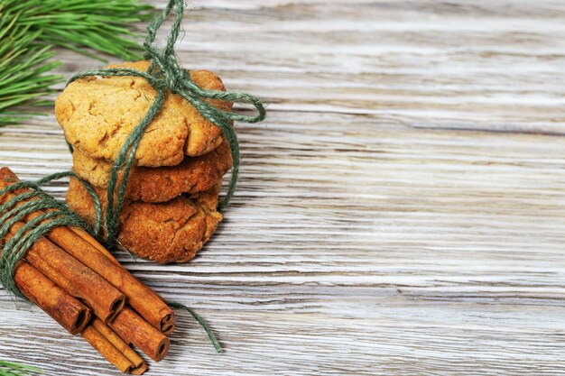 Montón de galletas redondas de pan de jengibre y palitos de canela decorados con ramas de pino en madera