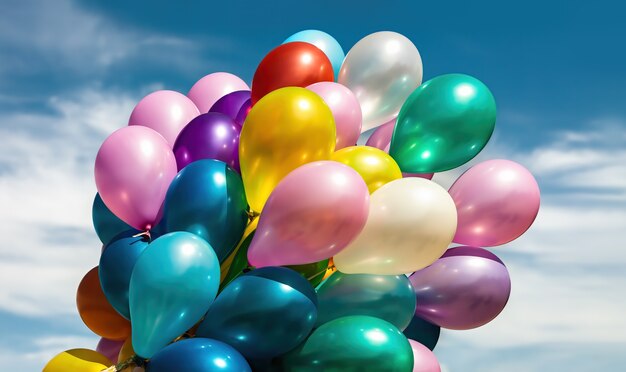 Un montón de globos de colores en el fondo del cielo azul con nubes