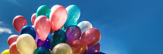 Un montón de globos de colores en el fondo del cielo azul con nubes