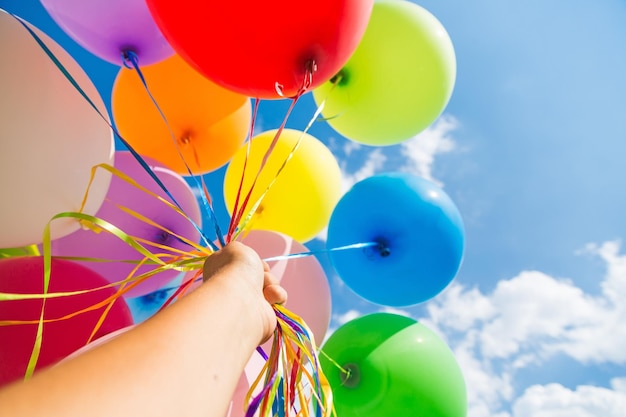 Montón de globos de colores en la mano en el fondo