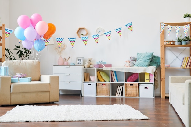 Montón de globos de colores y pila de giftboxes en un sillón en el salón decorado con banderas para la fiesta de cumpleaños en casa