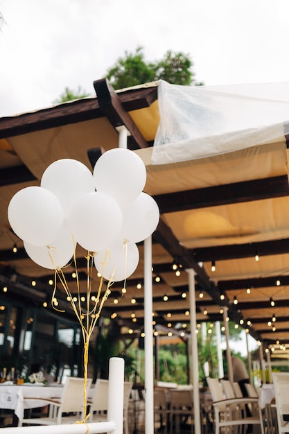 Un montón de globos de helio blanco en el fondo de las mesas en el restaurante y guirnaldas.