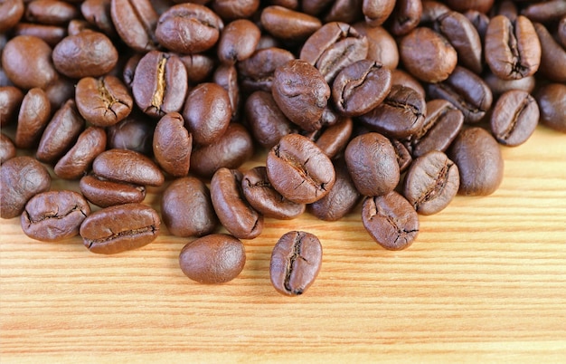 Foto montón de granos de café tostados sobre fondo de madera