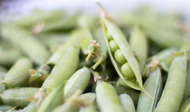 Un montón de guisantes verdes Primer plano de guisantes verdes jóvenes sin pelar Fondo verde Comida ecológica saludable