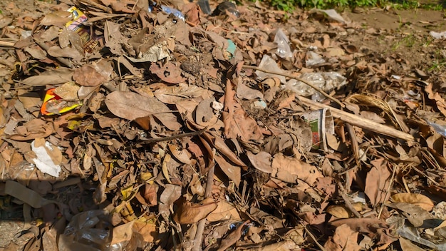 Un montón de hojas secas mezcladas con residuos plásticos