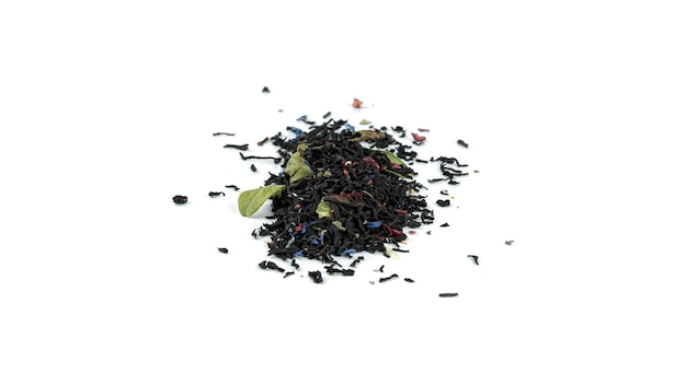 Montón de hojas de té negro con frutas sobre fondo blanco.