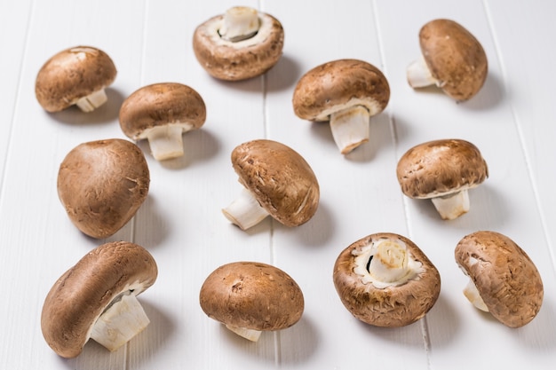 Un montón de hongos reales esparcidos sobre una mesa de madera blanca. Comida vegetariana. Hongos cultivados artificialmente.